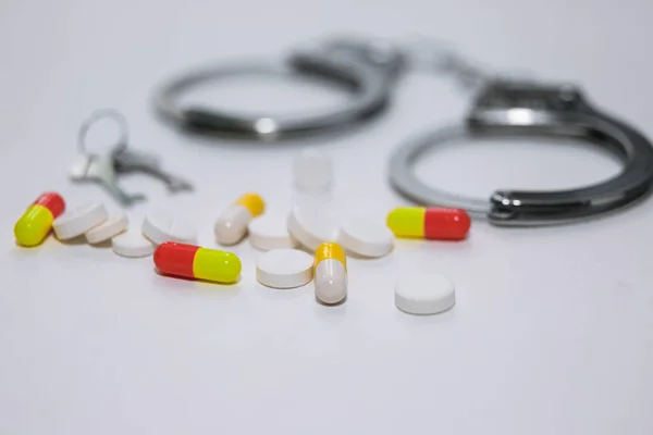 Esposas y pastillas y medicamentos en la mesa blanca. — Foto de Stock