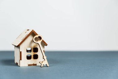 Emlak konsepti. Gri arkaplanlı ve kopya alanı olan küçük oyuncak ahşap ev