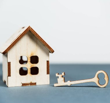 Emlak konsepti. Gri arkaplanlı ve kopya alanı olan küçük oyuncak ahşap ev