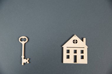 Emlak konsepti. Gri arkaplanlı ve kopya alanı olan küçük oyuncak ahşap ev