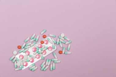 Çeşitli haplar, kapsüller ve tabletler pembe bir zemin üzerinde kabarcıklar ve metin için fotokopi alanı.