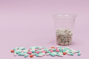 Metin için kopyalama alanı olan pembe bir zemin üzerinde çeşitli haplar ve kapsüller