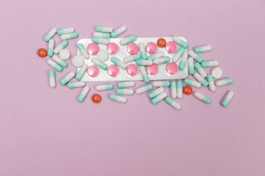 Çeşitli haplar, kapsüller ve tabletler pembe bir zemin üzerinde kabarcıklar ve metin için fotokopi alanı.