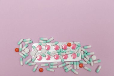 Çeşitli haplar, kapsüller ve tabletler pembe bir zemin üzerinde kabarcıklar ve metin için fotokopi alanı.