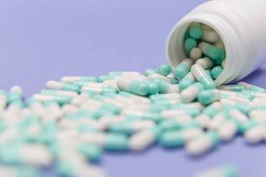 Mavi ve beyaz kapsül hapları beyaz plastik şişelerden döküldü. Küresel sağlık hizmeti kavramı. Antibiyotik ilaç direnci. Antimikrobik kapsül hapları. İlaç sanayisi. Eczane.