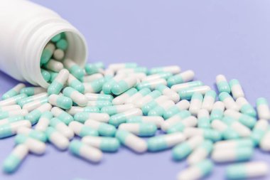 Mavi ve beyaz kapsül hapları beyaz plastik şişelerden döküldü. Küresel sağlık hizmeti kavramı. Antibiyotik ilaç direnci. Antimikrobik kapsül hapları. İlaç sanayisi. Eczane.