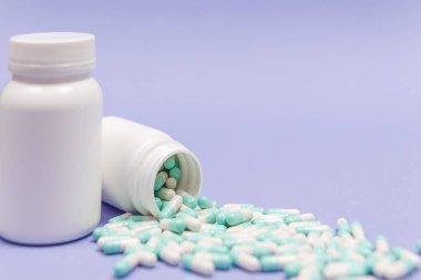 Mavi ve beyaz kapsül hapları beyaz plastik şişelerden döküldü. Küresel sağlık hizmeti kavramı. Antibiyotik ilaç direnci. Antimikrobik kapsül hapları. İlaç sanayisi. Eczane.