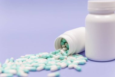 Mavi ve beyaz kapsül hapları beyaz plastik şişelerden döküldü. Küresel sağlık hizmeti kavramı. Antibiyotik ilaç direnci. Antimikrobik kapsül hapları. İlaç sanayisi. Eczane.