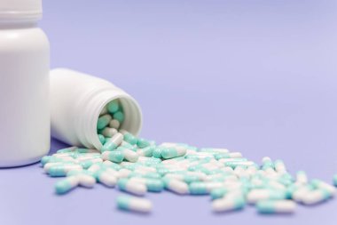Mavi ve beyaz kapsül hapları beyaz plastik şişelerden döküldü. Küresel sağlık hizmeti kavramı. Antibiyotik ilaç direnci. Antimikrobik kapsül hapları. İlaç sanayisi. Eczane.