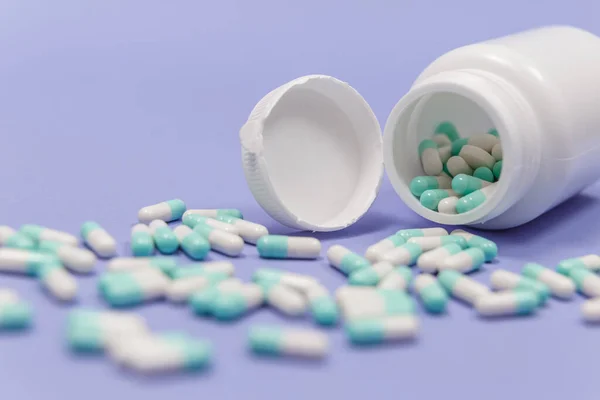 Μπλε Και Άσπρο Χάπι Κάψουλες Χυθεί Από Λευκό Πλαστικό Δοχείο — Φωτογραφία Αρχείου