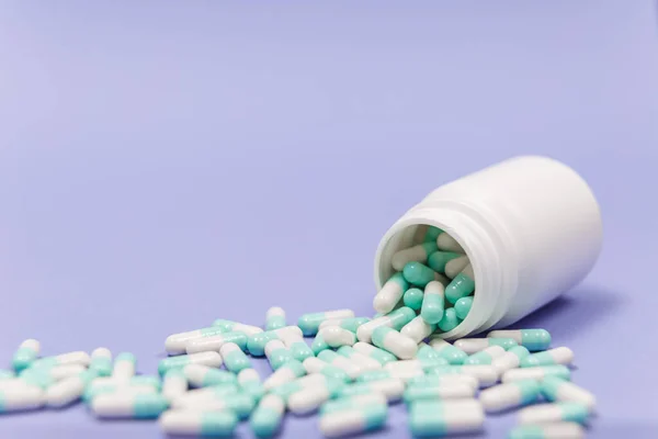 Μπλε Και Άσπρο Χάπι Κάψουλες Χυθεί Από Λευκό Πλαστικό Δοχείο — Φωτογραφία Αρχείου