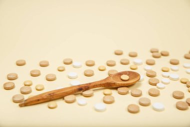 Kaşık hap ve kapsüllerle dolu. Pembe arka planda vitaminler ve takviyeler.