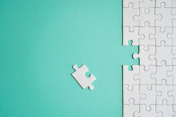 Kayıp yapboz parçaları. İş konsepti. Katlanmış beyaz yapboz parçası ve renkli bir yüzeyin arka planına karşı taranmamış bir yığın yapboz..