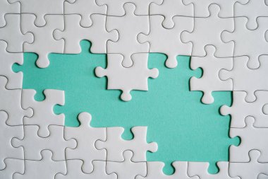 Kayıp yapboz parçaları. İş konsepti. Katlanmış beyaz yapboz parçası ve renkli bir yüzeyin arka planına karşı taranmamış bir yığın yapboz..