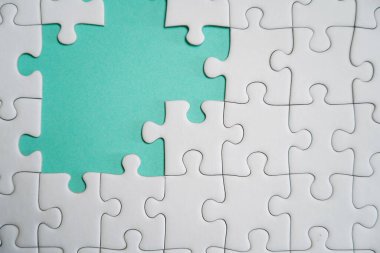 Kayıp yapboz parçaları. İş konsepti. Katlanmış beyaz yapboz parçası ve renkli bir yüzeyin arka planına karşı taranmamış bir yığın yapboz..