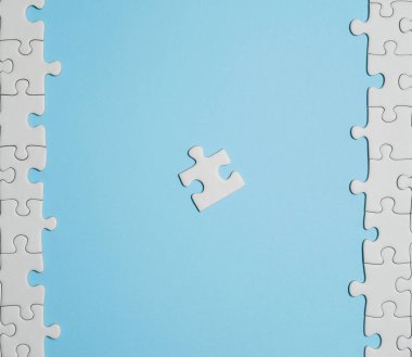 Kayıp yapboz parçaları. İş konsepti. Katlanmış beyaz yapboz parçası ve mavi bir yüzeyin arka planına karşı taranmamış bir yığın yapboz..