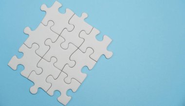 Kayıp yapboz parçaları. İş konsepti. Katlanmış beyaz yapboz parçası ve mavi bir yüzeyin arka planına karşı taranmamış bir yığın yapboz..