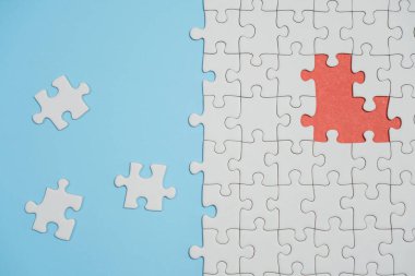 Kayıp yapboz parçaları. İş konsepti. Katlanmış beyaz yapboz parçası ve mavi bir yüzeyin arka planına karşı taranmamış bir yığın yapboz..