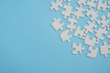 Kayıp yapboz parçaları. İş konsepti. Katlanmış beyaz yapboz parçası ve mavi bir yüzeyin arka planına karşı taranmamış bir yığın yapboz..