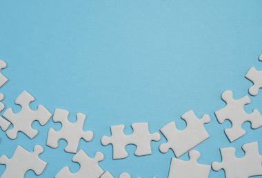 Kayıp yapboz parçaları. İş konsepti. Katlanmış beyaz yapboz parçası ve mavi bir yüzeyin arka planına karşı taranmamış bir yığın yapboz..
