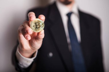 Bir adamın elinde altın Bitcoin, yeni sanal para biriminin dijital sembolü. Adam bitcoin işinden para aldı.