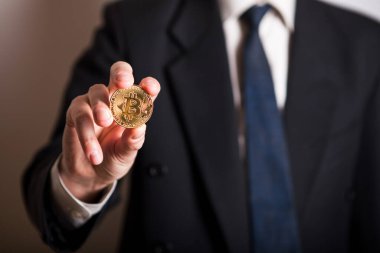 Bir adamın elinde altın Bitcoin, yeni sanal para biriminin dijital sembolü. Adam bitcoin işinden para aldı.
