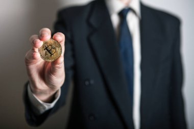 Bir adamın elinde altın Bitcoin, yeni sanal para biriminin dijital sembolü. Adam bitcoin işinden para aldı.