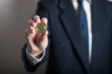 Bir adamın elinde altın Bitcoin, yeni sanal para biriminin dijital sembolü. Adam bitcoin işinden para aldı.