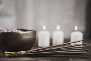 Koyu ahşap zemin üzerinde çakıl taşları olan mumlarla dolu şarkı kasesi..