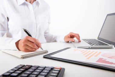 İş kadını, grafik belgesine yakından bakıyor. Ofis masasında otururken finansal şema, grafik ve iş çizelgeleri gösteren genç bir iş kadını.