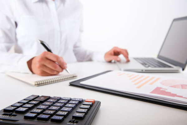 Деловая женщина указывает на крупный план. Молодая деловая женщина показывает финансовую диаграмму, график, бизнес-диаграммы во время конференции сидя на столе офиса