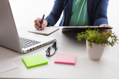 Elinde kalem tutan iş adamı grafik belgeleri ve gün batımı ışıklarıyla çalışıyor. Ofisteki tableti işaret eden borsa çizelgesi ve parmak izi.