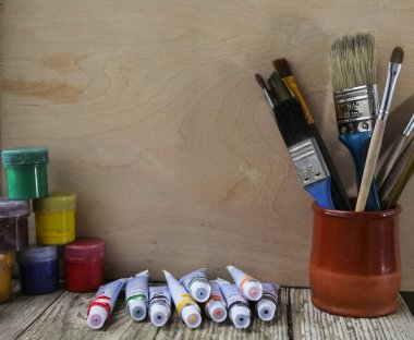 Masada farklı renkte fırçalar, ahşap arka plan. Temiz boyacı işyeri çizim için hazır.