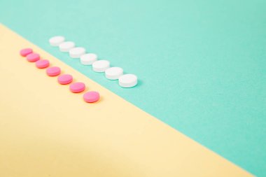 Renkli arka planda beyaz ve pembe ilaçlar.