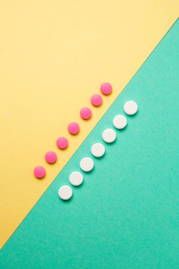Renkli arka planda beyaz ve pembe ilaçlar.