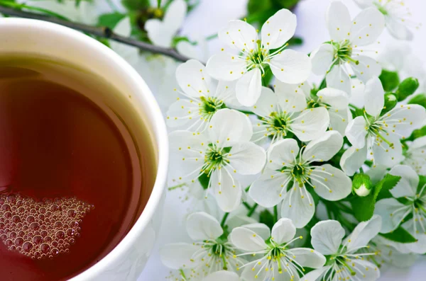 Tea with cherry flowers and branches on white table, top view — Stock Photo, Image