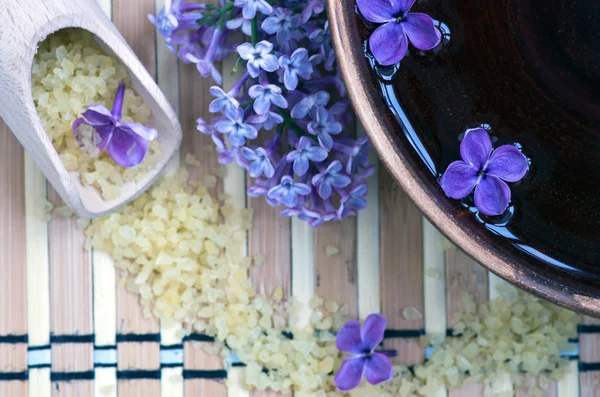 Flores em uma tigela de cor marrom com sal marinho para SPA — Fotografia de Stock