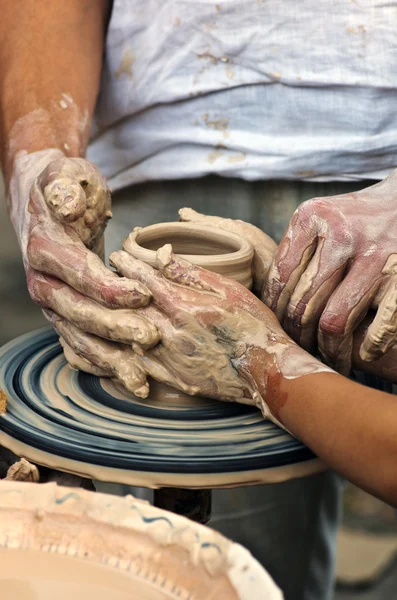 De handen van een pottenbakker helpen het kind maken een werper op een pottenbakkerij — Stockfoto