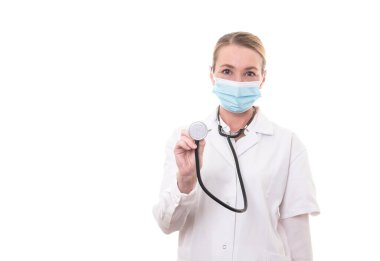Beyaz üniformalı ve steteskoplu genç bir doktor, izole edilmiş arka planda maske takıyor.