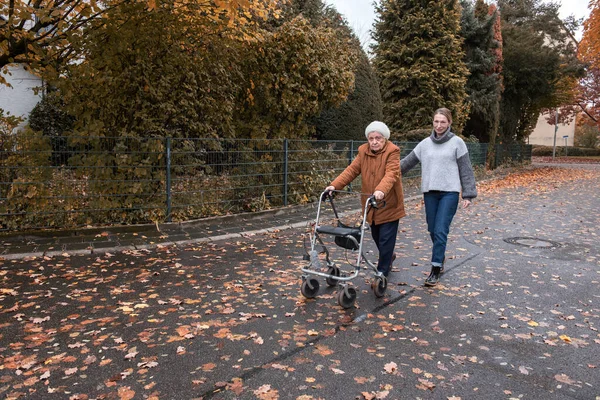 冬に歩行者の助けを借りて孫娘と散歩をしている高齢女性 — ストック写真