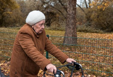 Yaşlı bir kadın temiz havanın tadını çıkarmak için sonbaharda yürüyüş yapıyor.