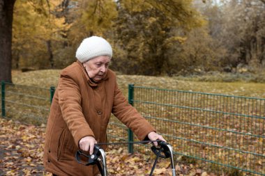 Yaşlı bir kadın temiz havanın tadını çıkarmak için sonbaharda yürüyüş yapıyor.
