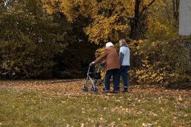 Yaşlı bir kadın kışın bir yürüyüşçünün yardımıyla torunuyla yürüyüşe çıkıyor.