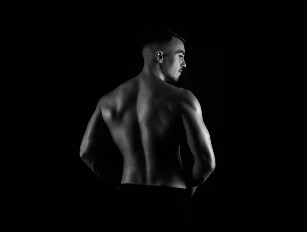 黒の背景に立って筋肉を持つハンサムな若いボディビルダー — ストック写真