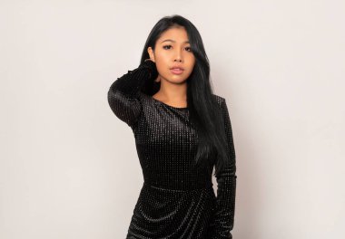 Gri arka planda uzun siyah saçlı güzel Asyalı kadın poz veriyor.