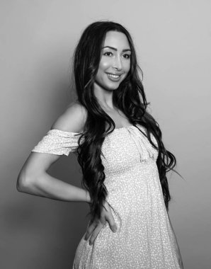 Gri arka planda uzun siyah saçlı ve doğal makyajlı güzel bir kadın. 