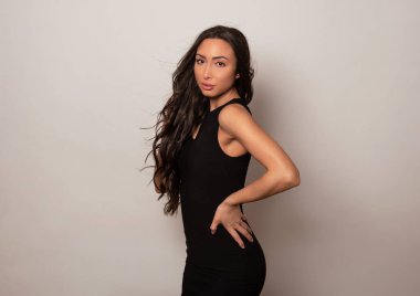 Gri arka planda uzun siyah saçlı ve doğal makyajlı güzel bir kadın. 