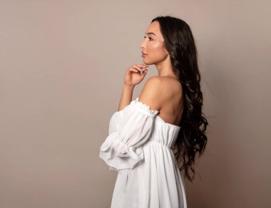 Gri arka planda uzun siyah saçlı ve doğal makyajlı güzel bir kadın. 