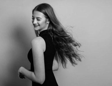 Gri arka planda uzun, parlak ve sağlıklı saçları olan güzel bir genç kadın.