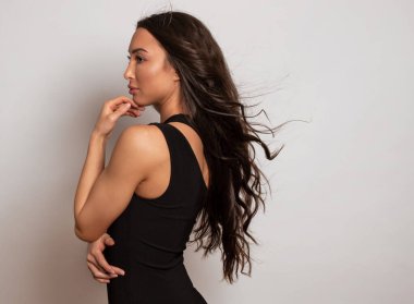 Gri arka planda uzun siyah saçlı ve doğal makyajlı güzel bir kadın. 